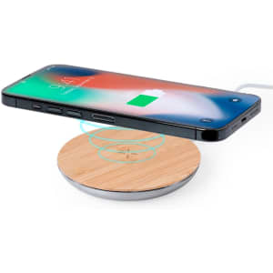 A wireless charger with a wooden base and a silver circular edge, featuring a smartphone positioned above it.