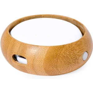A round bamboo charging dock with a white surface and a small connector opening, designed for electronic devices.