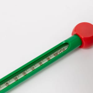 A green soil thermometer with a red top, featuring a clearly marked temperature scale.
