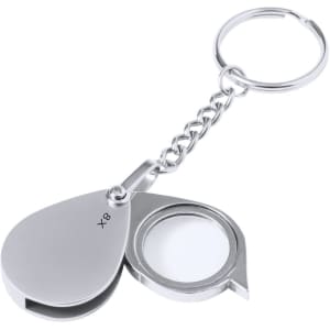 A silver keyring magnifier with an 8x lens attached to a chain. The lens is housed in a sleek, compact case.