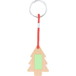 A keyring shaped like a Christmas tree in natural wood with a green patch and red cord attachment.