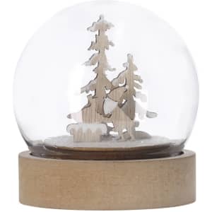 A snow globe featuring wooden trees and a snowy base, enclosed in a clear dome with a light wood base.