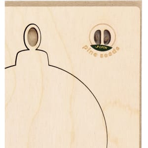 A wooden Christmas card decoration in the shape of an ornament, featuring a hole for hanging and pine seeds inside.
