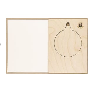 A wooden Christmas card decoration in the shape of an ornament with a blank interior for messages.