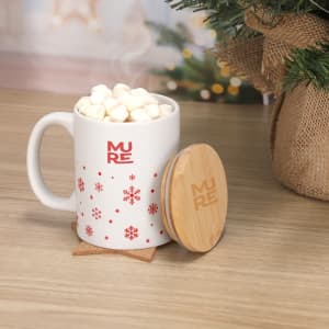 A white coffee mug with festive red snowflake patterns and a bamboo lid, filled with marshmallows.