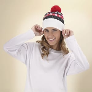 A woman wearing a white, red, and black beanie with a pom-pom on top. The hat features festive patterns and has a logo.