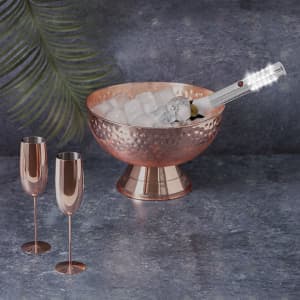 A copper bowl filled with ice and a Pexel Led Stick, accompanied by two elegant copper champagne flutes.