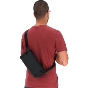 A black Koket Bag worn crossbody by a person in a red shirt, featuring a strap and a sleek design.