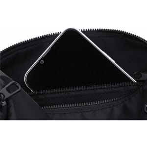 A black Koket Bag featuring a zippered pocket with a smartphone inside. The interior is sleek and functional.
