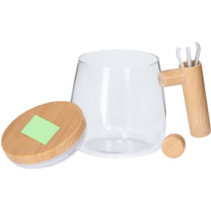 A transparent mixing mug with a wooden lid and handle, accompanied by a small wooden tool set.