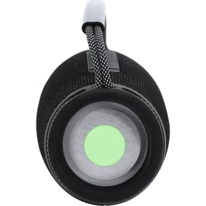 A black portable speaker with a textured surface and a green accent at the base. It features a durable handle for carrying.