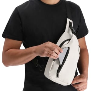 A person holding a white Soplex Shoulder Bag with a zippered pocket being opened. The bag features a logo.