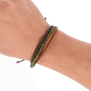 A wrist features three bracelets in dark green, black, and brown tones, with textured and smooth surfaces.
