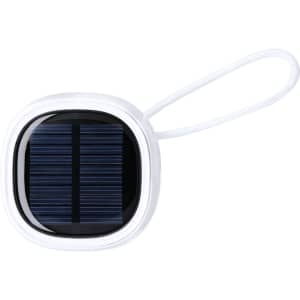 A compact white speaker with a solar panel design and a loop for attachment. It features a branding logo.