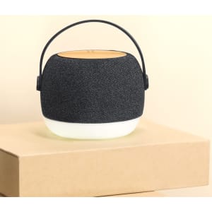 A portable speaker with a dark fabric exterior and a white base, featuring a carry handle on top.