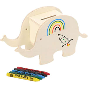 An elephant-shaped money box in natural wood with a rainbow and rocket design, accompanied by colourful crayons.