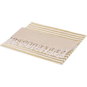 A folded bath towel with a striped pattern in gold and white, featuring fringed edges. It has a logo.