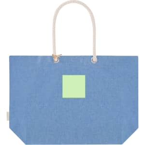 A blue tote bag with a square green patch and rope handles. It has a minimalist design and features a logo.