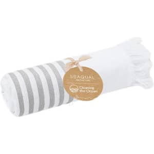 A rolled towel with white and grey stripes, featuring tassels at one end and a natural tag.