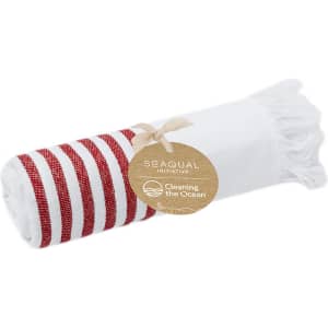 A rolled towel featuring white fabric with red stripes, accompanied by a tag indicating its eco-friendly initiative.