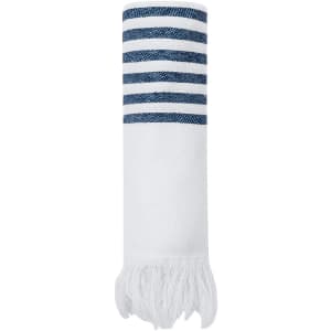 A rolled white towel with navy blue stripes and fringing at one end, suitable for beach use.
