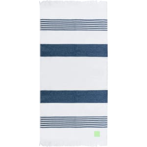 A striped towel in white and navy blue, featuring a fringed edge and a small logo on the corner.