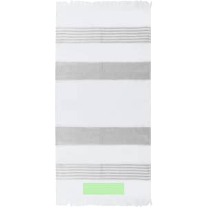 A white towel with grey stripes and a small green label at the bottom. It is soft and lightweight, ideal for beach use.