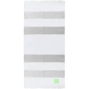 A striped towel in white and grey with fringed edges, featuring a small green logo.