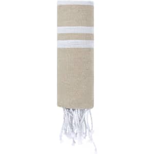 A beige towel pareo with white stripes and decorative fringes at the bottom, featuring a logo.