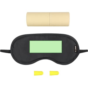 A black sleep mask, yellow earplugs, and a cylindrical tube are arranged together on a flat surface.