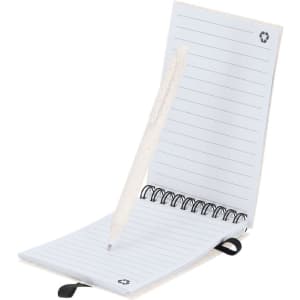 A notebook with lined pages and a white pen, featuring a circular logo. The cover is a light colour.