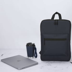 A navy insulated cup with a black lid beside a grey laptop and a dark backpack on a marble surface.