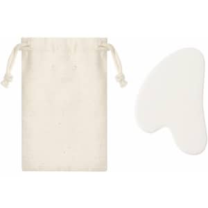A white gua sha face massager beside a cream drawstring pouch. The massager has a smooth, curved shape.