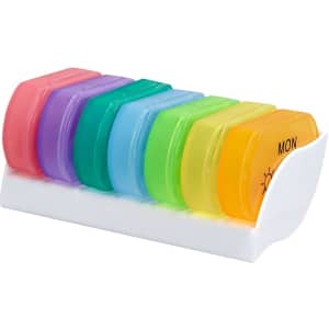 A colourful pillbox with seven compartments in pink, purple, blue, green, and orange, housed in a white base and featuring a logo.