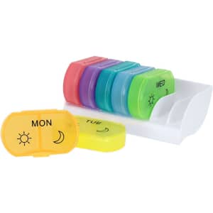 A multi-coloured pillbox with compartments for each day of the week, displayed on a white organiser.