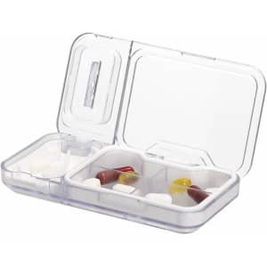 A transparent pillbox featuring multiple compartments, containing various coloured tablets and capsules. It has a simple design.