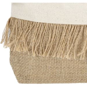 A toiletry bag featuring a textured natural jute material with fringed detailing along the top edge.