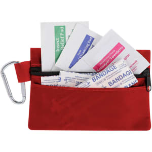 A red first aid kit contains various items, including bandages, antiseptic wipes, and insect relief pads, with a carabiner.