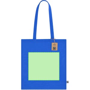 A blue tote bag with a blank green panel in the centre and two shoulder straps. It features a logo.