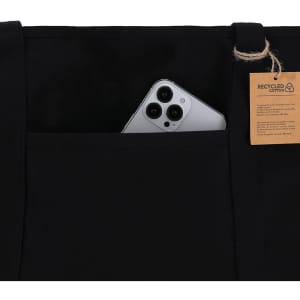 A black tote bag featuring a pocket with a smartphone partially visible and a tag indicating recycled cotton.