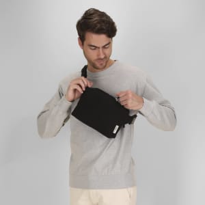A black shoulder bag being opened by a person wearing a grey sweatshirt, set against a neutral background.