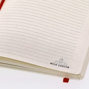 A notepad with cream-coloured lined pages and a red ribbon bookmark, featuring a logo indicating recycled material.