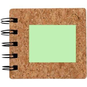 A cork notepad with black spiral binding and a light green sticky note section.