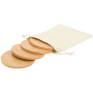 A set of four wooden coasters in a cream drawstring bag. The coasters are circular and made from light wood.