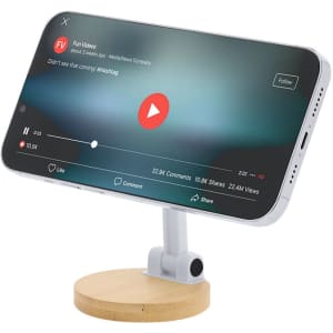 A white phone stand with a bamboo base, supporting a smartphone displaying a video on screen.