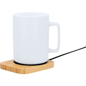 A white mug sits on a bamboo base with a black cord, designed as a cup warmer.