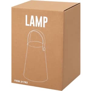 A brown cardboard box containing a lamp with a handle. The box has a simple line drawing of the lamp on it.