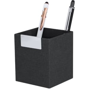 A square black pencil holder with a silver label, containing a white pen and a black pen.