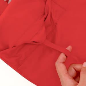 A red rain jacket with a pocket and a visible hand holding the interior lining, featuring a logo.