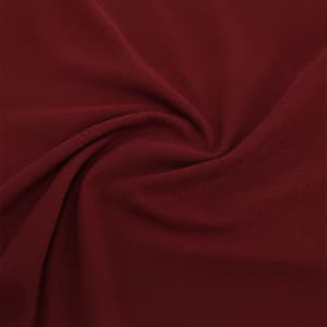 A close-up of burgundy fabric, showcasing its smooth texture and stretch. The material is soft and pliable.